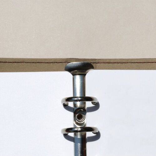A close-up of the binder's metal ring mechanism reveals a shiny silver finish, with a beige fabric spine and white pages with rounded corners visible below.