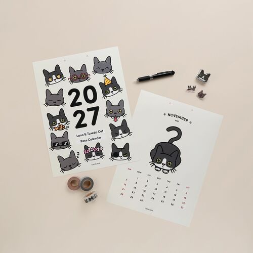 The image features a playful collection of cat-themed stickers and calendar sheets, displayed on a neutral beige background with minimal accessories.