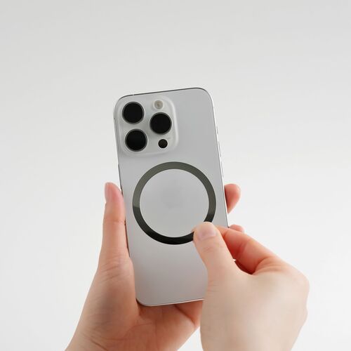 A hand holds a sleek, silver iPhone with a black Seattle Magnetic Phone Grip attached, emphasizing its modern design and magnetic functionality.