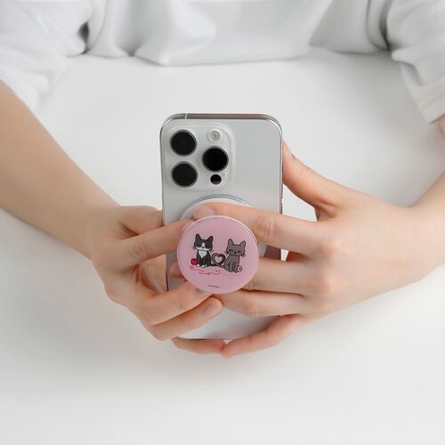 Hands hold a sleek, white smartphone with a pink, cartoon cat-themed magnetic grip attached, set against a clean, white background.