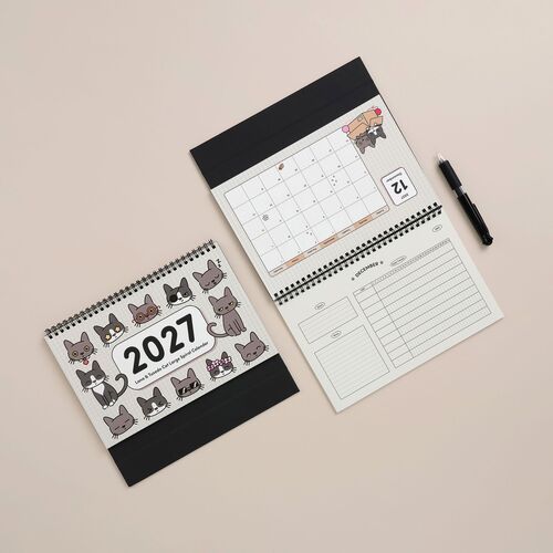 The open calendar reveals detailed monthly layouts with playful Lana & Tuxedo cat illustrations, accented by clean lines and vibrant colors.