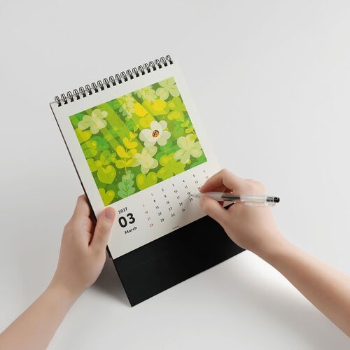 The calendar displays a vibrant, nature-inspired illustration with lush green foliage and a ladybug, set against a clean white background.