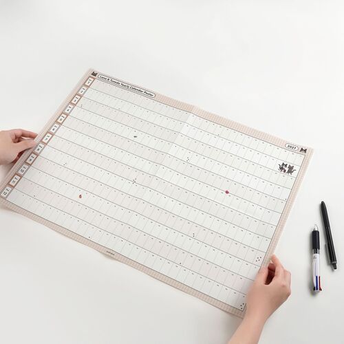 Hands hold the Horizontal layout beside a pen, showing its long rows and generous spaces for writing across each month.
