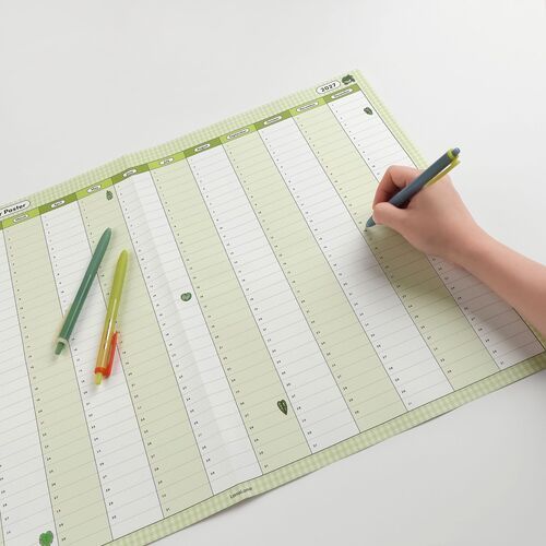 Pens rest on the calendar as someone writes in the Vertical style, highlighting its long monthly columns and generous note space.