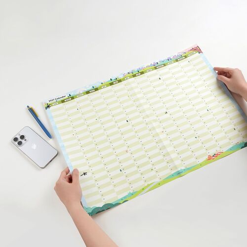 Hands hold the poster open beside a smartphone and pen, giving a clear sense of its large A2 planning format.