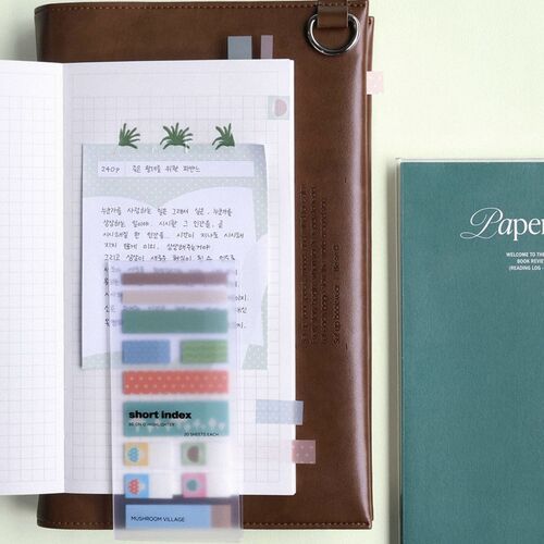 The image showcases a sheet of colorful sticky notes with playful patterns, placed on an open grid notebook, highlighting their decorative and functional use.