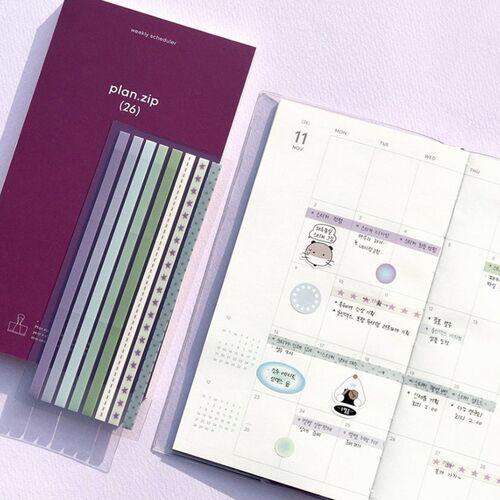 The image showcases a set of decorative long sticky notes with colorful patterns, partially torn, next to an open planner page on a soft pink background.