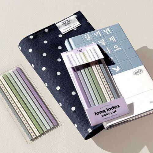 The image showcases a set of colorful, decorative long sticky notes with perforation lines, placed on a textured surface alongside a patterned fabric pouch.