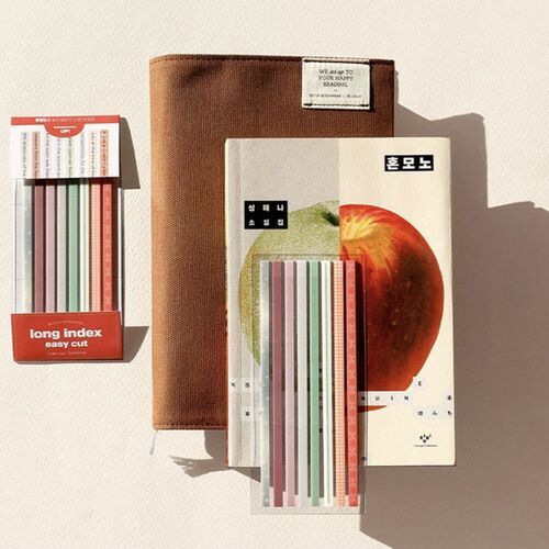 Colorful, patterned long sticky notes with perforated lines are displayed alongside a textured brown pouch and a book, casting soft shadows.