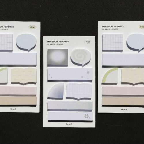 Three sheets of mini sticky note samples display distinct designs in soft pastel hues with subtle textures, set against a dark background.
