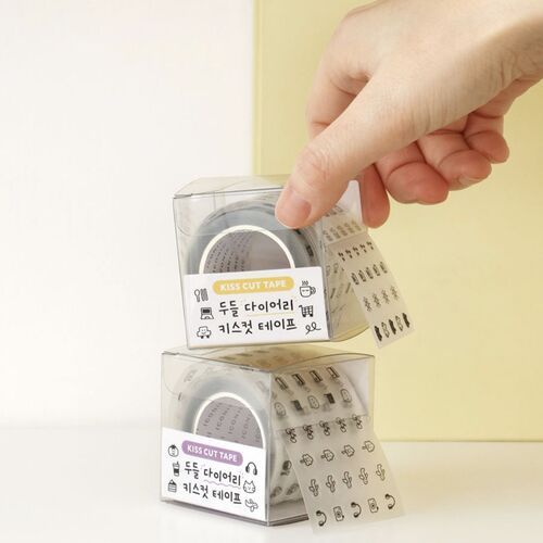 Clear plastic cases showcase the adorable doodle tape rolls with cute icons and Korean labels, emphasizing their playful design and versatility.