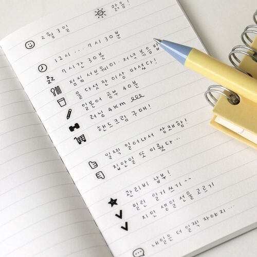 A neatly handwritten journal page featuring cute icons and Korean text, with a pastel yellow and blue pen resting on the paper.