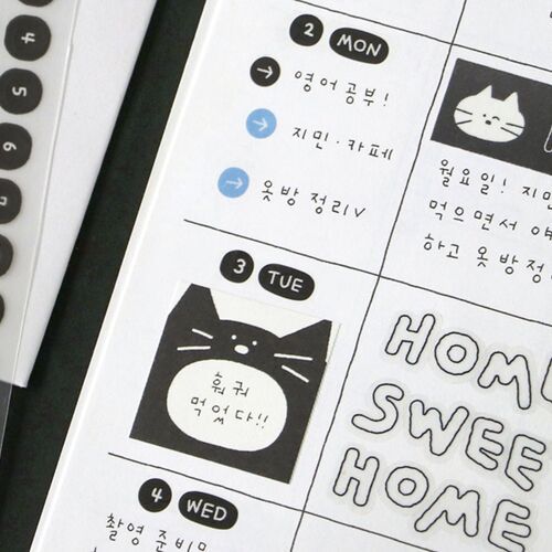 A detailed close-up reveals the black matte sticker sheet with playful doodle illustrations, alongside hints of the tape dispenser and colorful planner background.