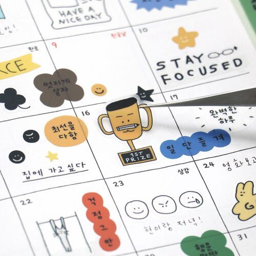 Colorful, playful stickers featuring cheerful characters and motivational phrases are arranged on a calendar page, adding a lively touch.