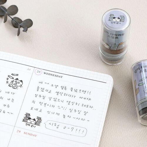 Two transparent self-inking cat stamps with playful illustrations are showcased beside a handwritten planner page, emphasizing their cute design and functionality.