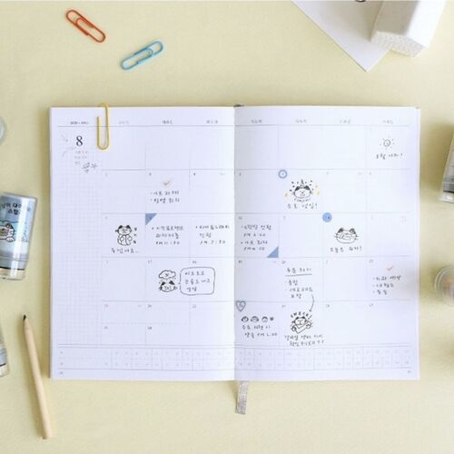 The image showcases a weekly planner decorated with various cute cat-themed self-inking stamps, surrounded by colorful paper clips and ink stamps.