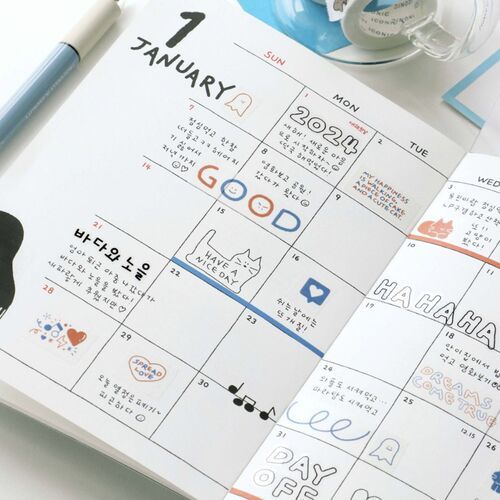 The calendar page features colorful doodle illustrations and handwritten notes, with a pastel blue pen and transparent tape dispenser nearby.