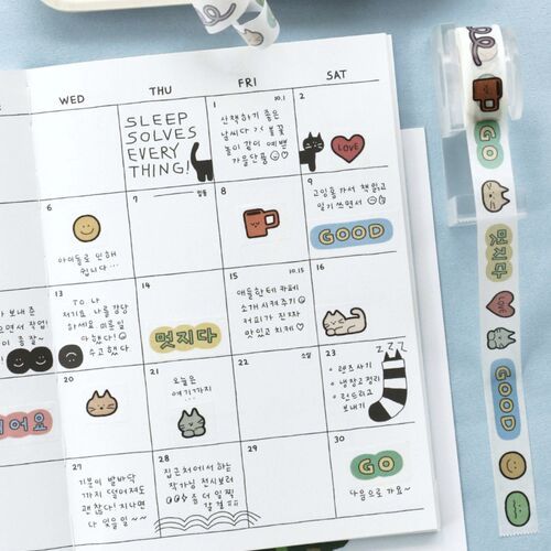 The tape features adorable doodle characters like cats, hearts, and stars in pastel colors, adding a playful touch to the planner page.