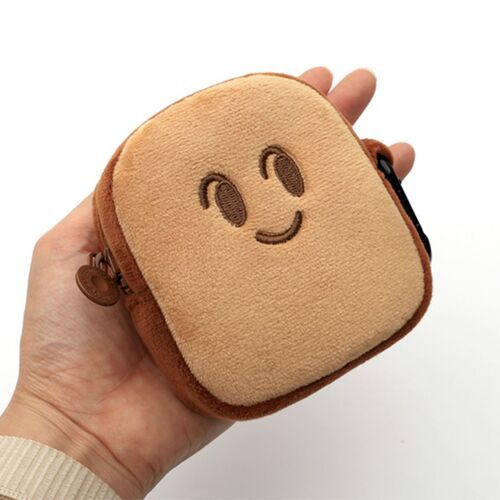 A hand holds a small, plush toast-shaped pouch with a smiling face, showcasing its soft, cushioned texture and adorable design.