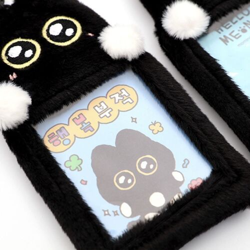 The plush black cat features shiny, embroidered eyes, white pom-poms on ears, and a clear PVC window displaying a cute photocard inside.