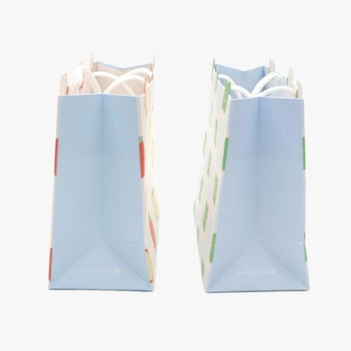 Two small gift bags with pastel blue backgrounds showcase apple and clover patterns, highlighting their cheerful designs and die-cut handles.
