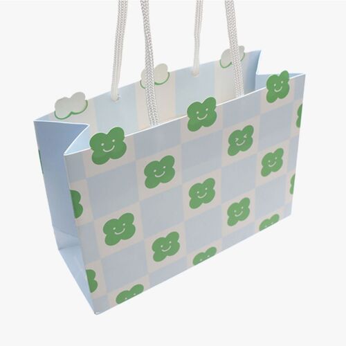 This gift bag features a playful light blue and white checkered pattern adorned with cheerful green clover and cloud motifs, with white twisted handles for easy carrying.