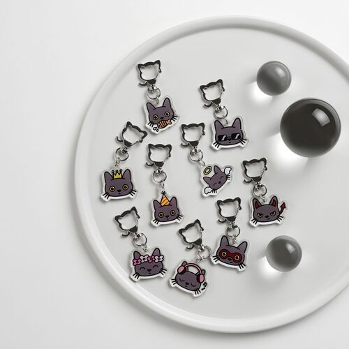 Several Lana Cat emoji acrylic key rings are displayed on a white circular tray, showcasing their vibrant colors and playful expressions.