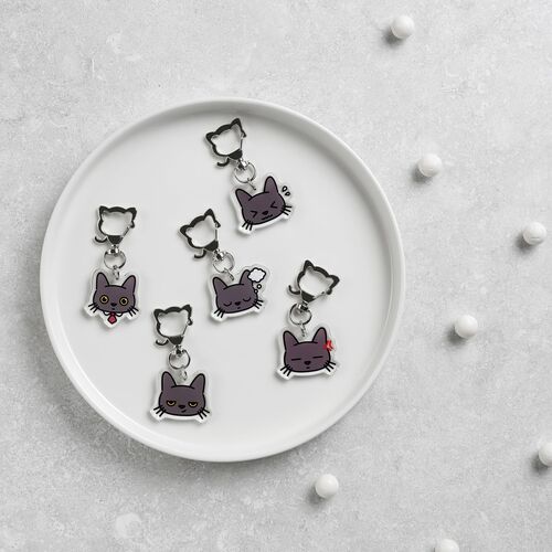 Multiple Lana Cat emoji acrylic key rings with expressive faces are arranged on a white dish, highlighting their vibrant colors and playful designs.