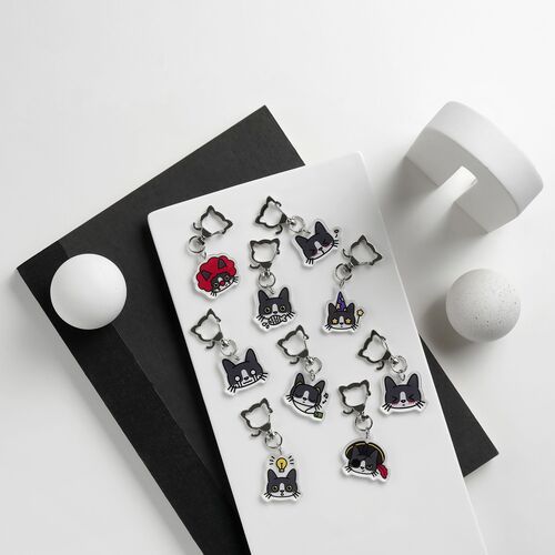 Colorful acrylic key ring featuring multiple cute tuxedo cat emoji faces with expressive details, arranged on a white surface.