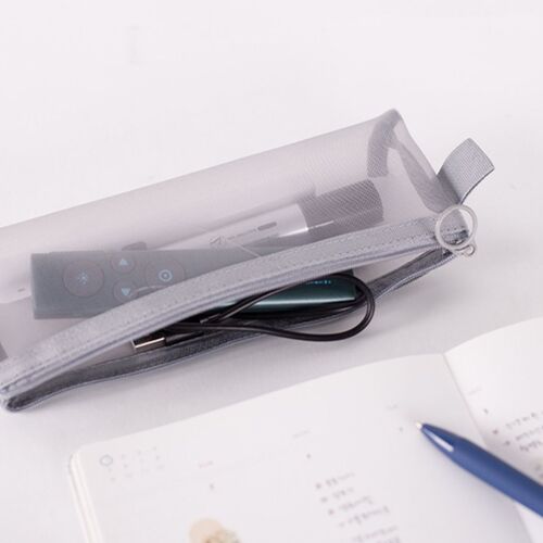 Transparent mesh pouch with a gray zipper and pull tab, containing a remote, cables, and a pen, placed on a white surface with an open notebook nearby.