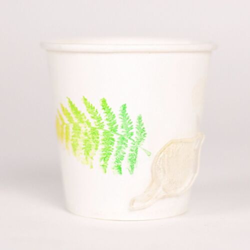 A white paper cup featuring a vibrant green fern print and a subtle beige leaf accent, set against a plain background.