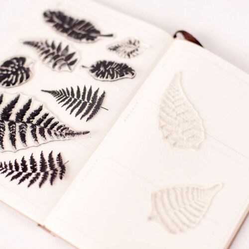 Open notebook displaying a collection of black and white fern and leaf stickers, emphasizing detailed botanical designs for nature-inspired crafts.