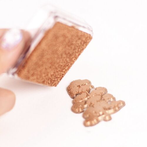 A close-up of a bronze metallic shimmer stamp pad with a textured surface, positioned at an angle on a white background.