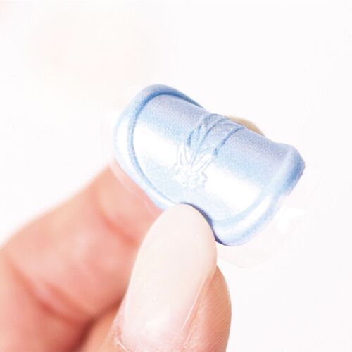 A close-up of a single blue sealing wax sticker with embossed floral and word details, held between fingers against a white background.