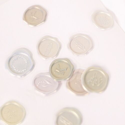 Clear wax seal stickers with embossed floral and word designs, arranged on a white surface highlighting their elegant, glossy finish.