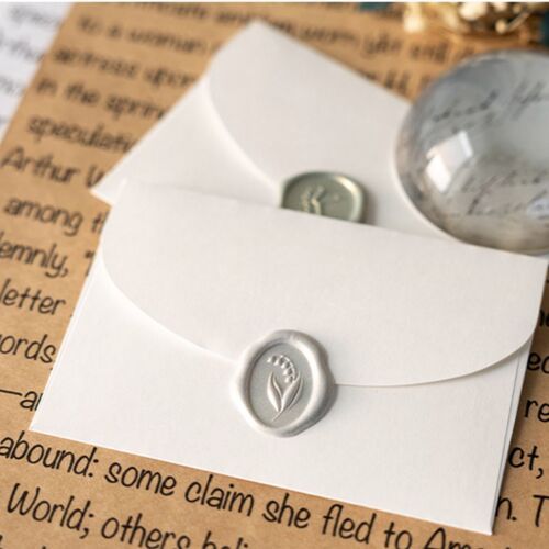 Close-up of two elegant sealing wax stickers with embossed floral and word designs, set against a background of handwritten text and paper textures.