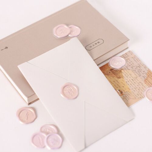 Pink, gold, and silver sealing wax stickers with embossed floral and word designs are displayed on a neutral background, highlighting their decorative appeal.