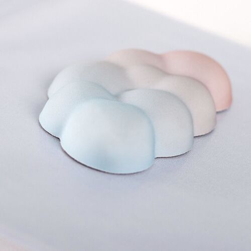 Soft pastel clouds in shades of light blue, white, and pale pink are delicately layered on a smooth white surface, evoking a calming sunset sky.
