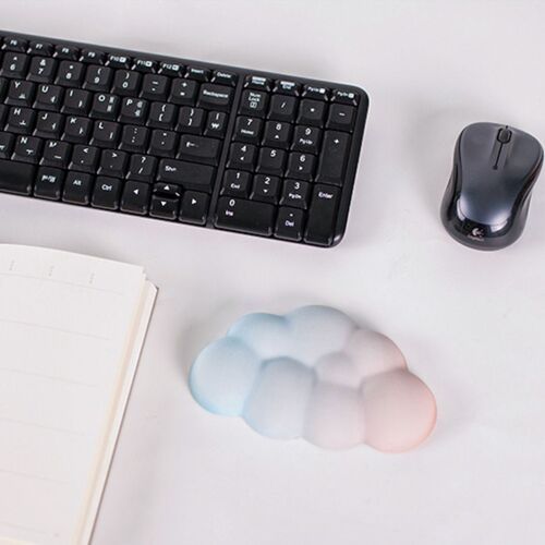 The Sunset Cloud Wrist Cushion features a soft pastel gradient with a cloud-like shape, placed near a keyboard and mouse on a clean workspace.