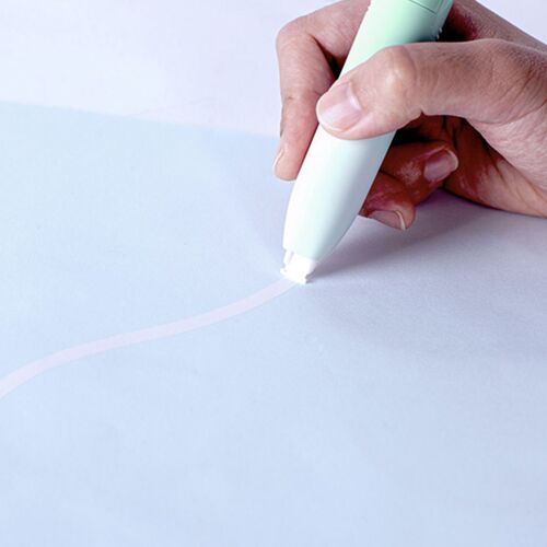 A hand holding the pastel mint correction tape, poised to glide it over a light blue sheet, emphasizing its smooth application.