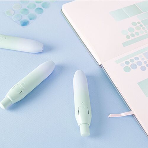 The correction tape features a pastel gradient design with a smooth, matte finish, shown with the top button ready to click on a soft blue background.