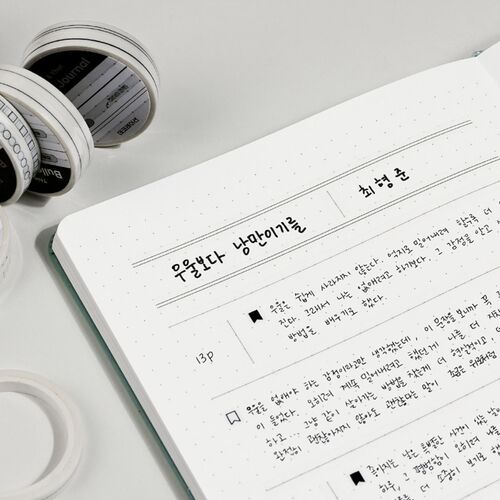 The open journal includes handwritten notes and tracker marks, with tape rolls positioned nearby for reference.