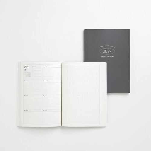 A sleek, dark gray planner with a minimalist cover displaying white text, open to reveal clean, organized weekly and grid pages.