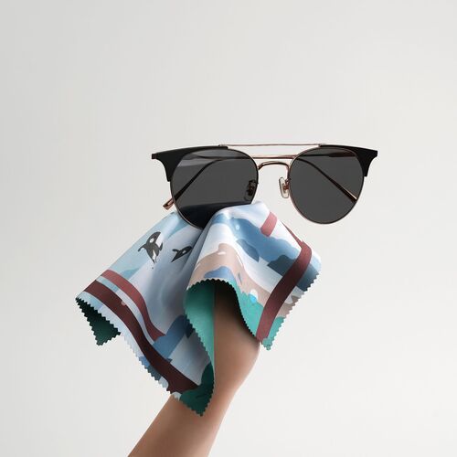 Sunglasses rest on the printed microfiber cloth, illustrating its everyday use for cleaning lenses and other delicate surfaces.
