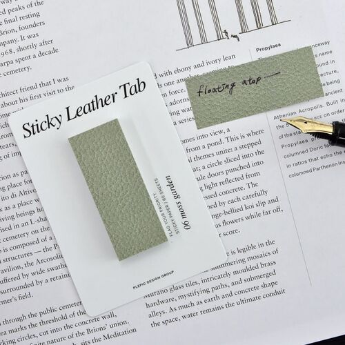 A Moss Garden Bar sample is held in hand, making its compact vertical format and printed leather texture easy to see.