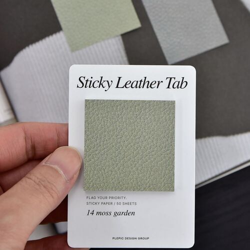 A hand holds the Moss Garden Square card against an open book, showing the paper scale and tactile printed surface.