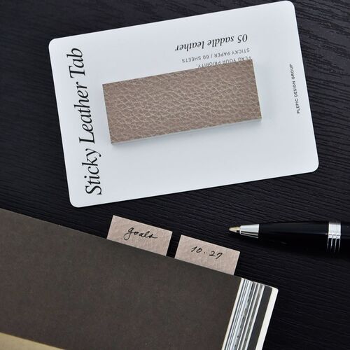 A Purple Velvet Bar note sits beside a pen and book, showing its textured surface and narrow bookmark-like proportions.