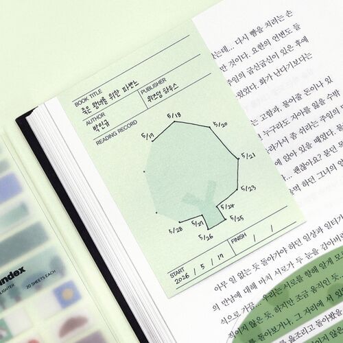 A green bookmark lies inside an open book, with its book information fields and dated dot-to-dot outline clearly visible.