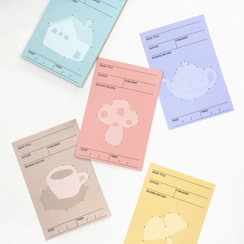 A pink bookmark rests beside a compact stack of books, while several colored sheets peek from between the pages.