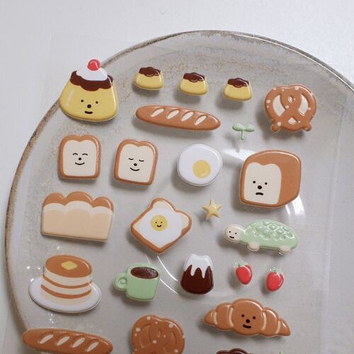 The stickers are arranged on a round plate, making the glossy finish and varied food shapes easy to see.